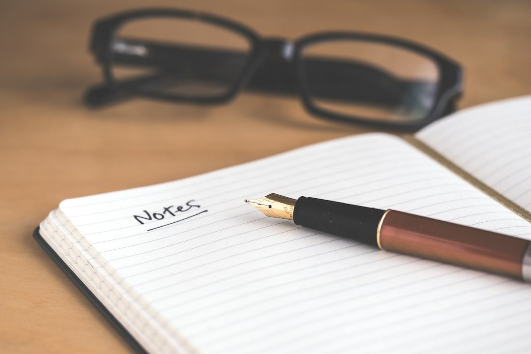 Handwritten notes in a notebook with a fountain pen and glasses.